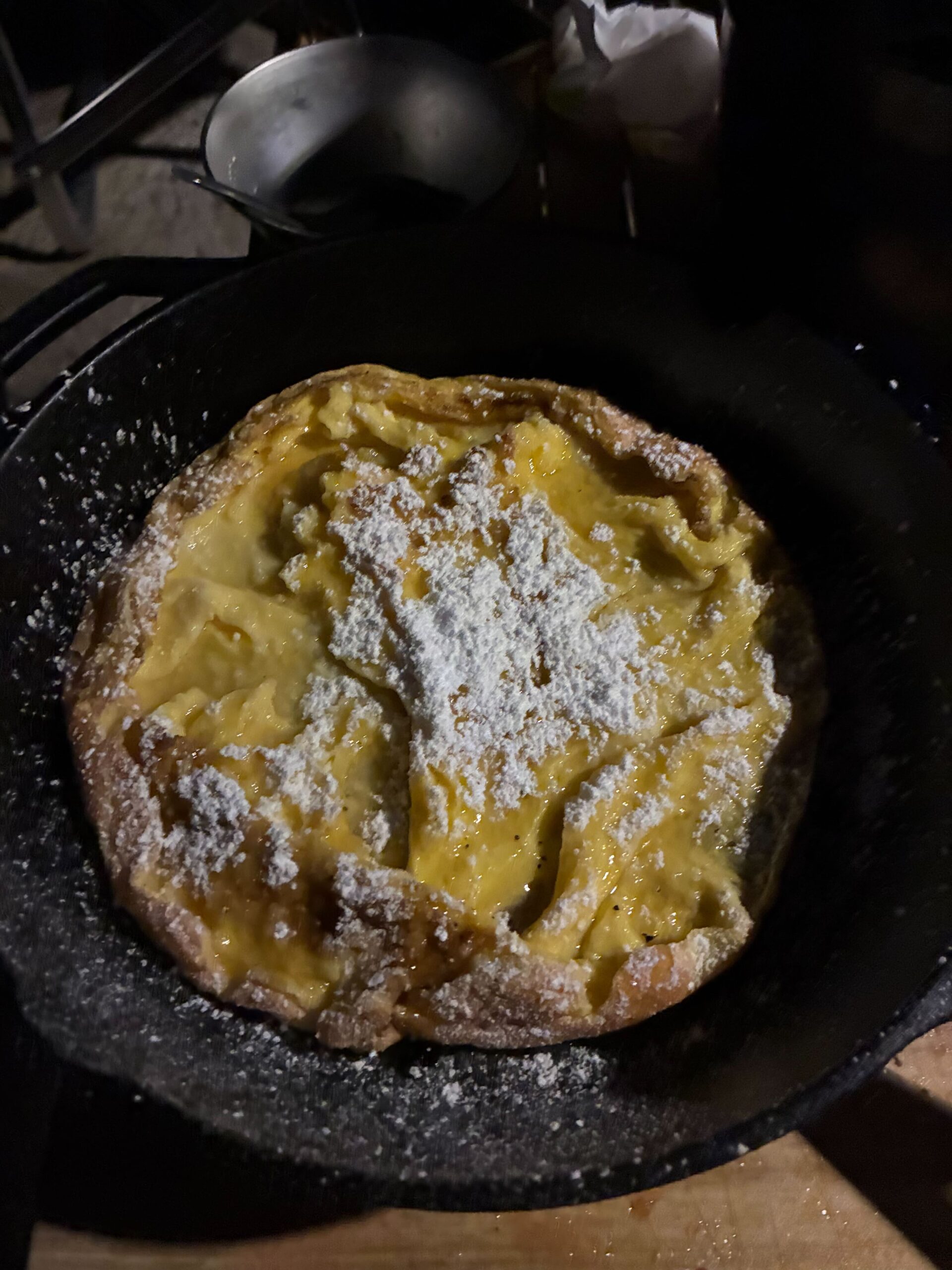 スキレットで焼かれたダッチベイビーに粉糖がかけられている様子