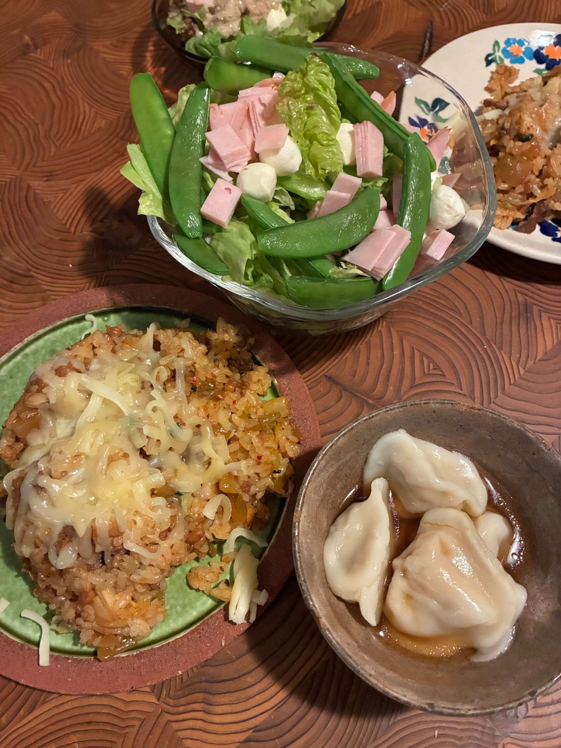 手作りの水餃子、チーズ炒飯、スナップエンドウのサラダが並んだ温かい食卓