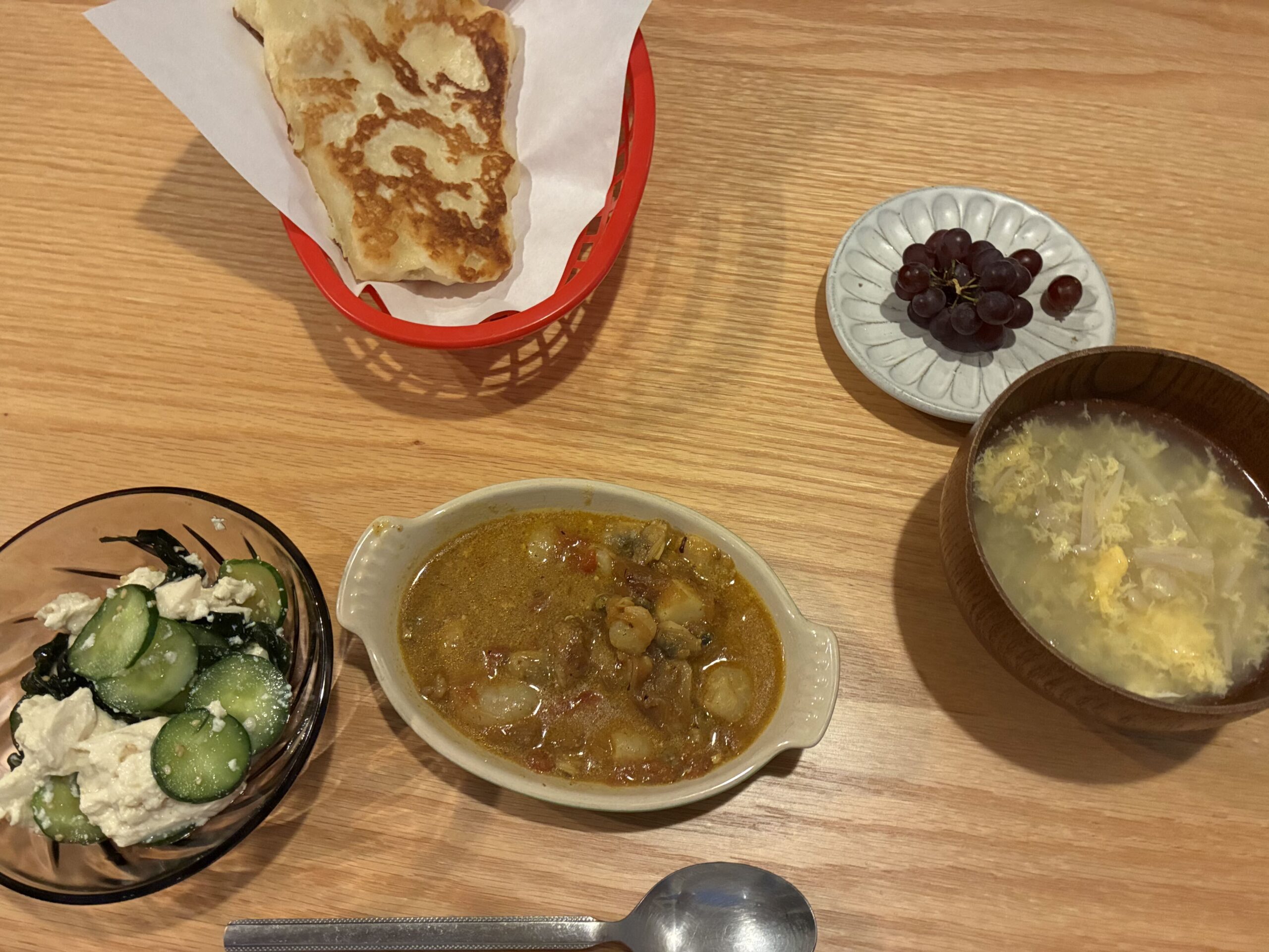 テーブルに並べられたアジアン料理の数々。カレー、ロティ、スープ、和え物などが並ぶ。