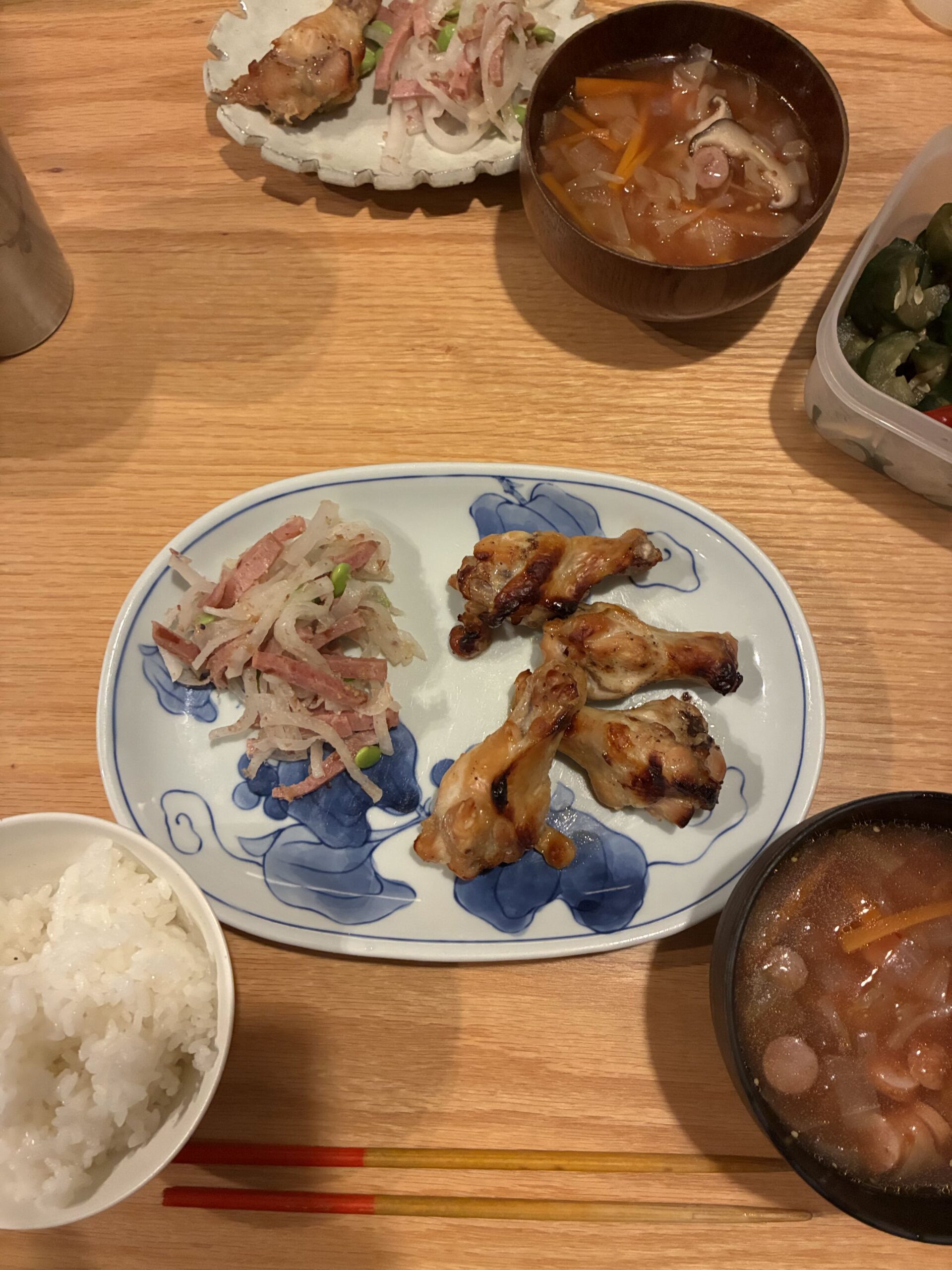 鶏手羽元のグリル、大根サラダ、具沢山の汁物、白米が並んだ温かみのある食卓