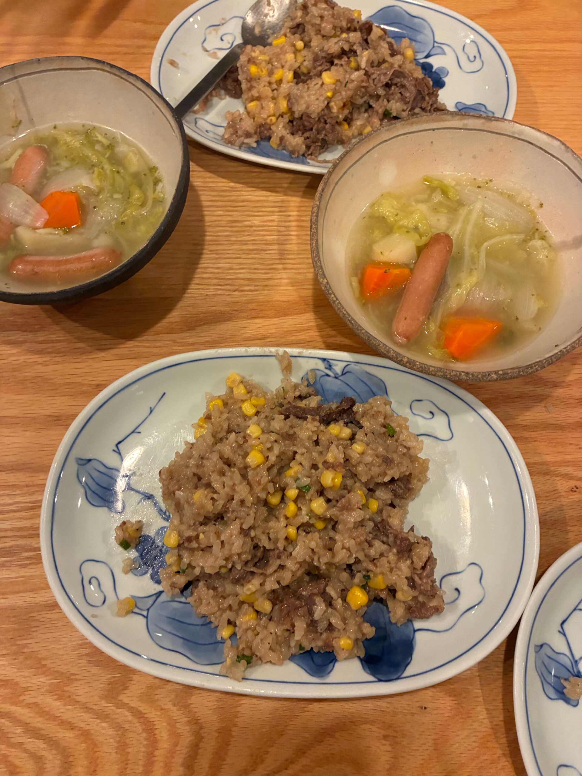 食卓に並んだペッパーランチ風焼飯とポトフ。青い模様の皿に盛り付けられている。