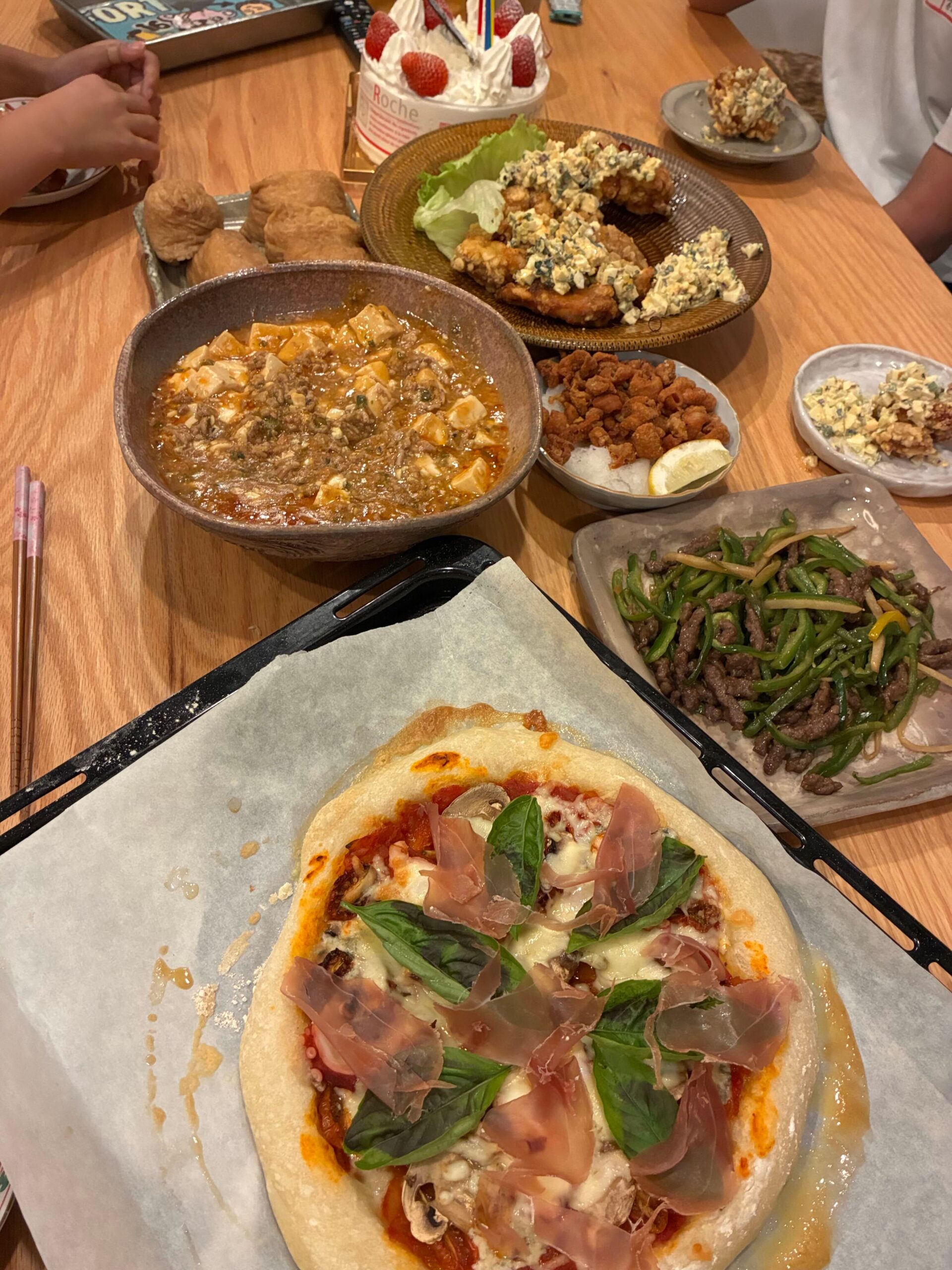 手作りピザと麻婆豆腐、青椒肉絲、唐揚げ、バースデーケーキが並ぶ賑やかな誕生日の食卓