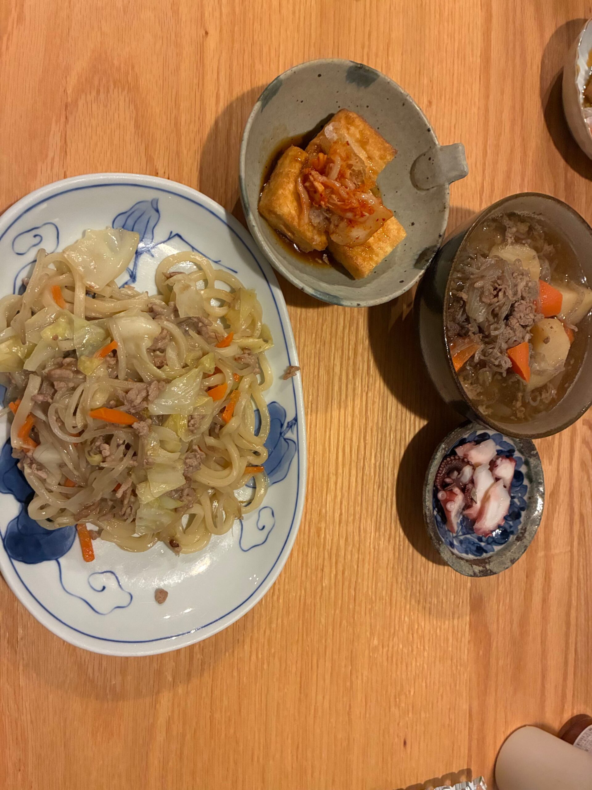 具沢山の焼きうどんと肉じゃが、揚げ出し豆腐、タコの小鉢が並んだ家庭の食卓
