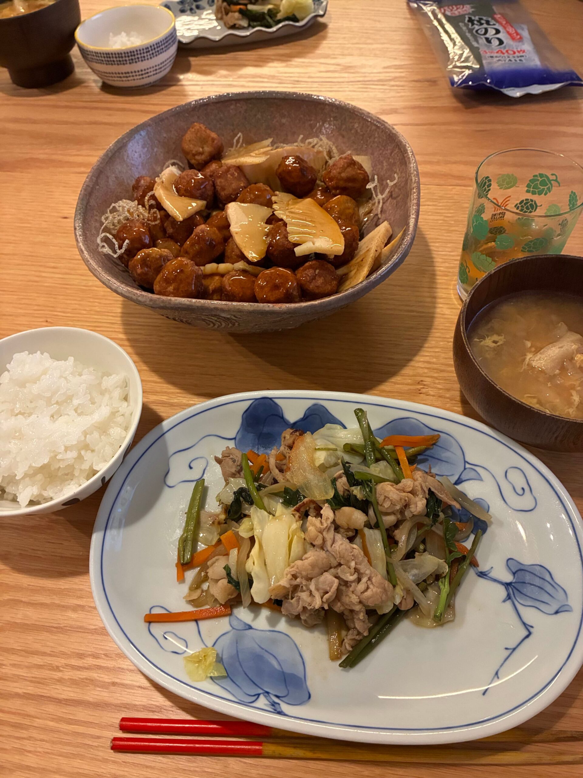 肉団子の甘酢あんと野菜炒め、ごはん、味噌汁が並んだ食卓の写真