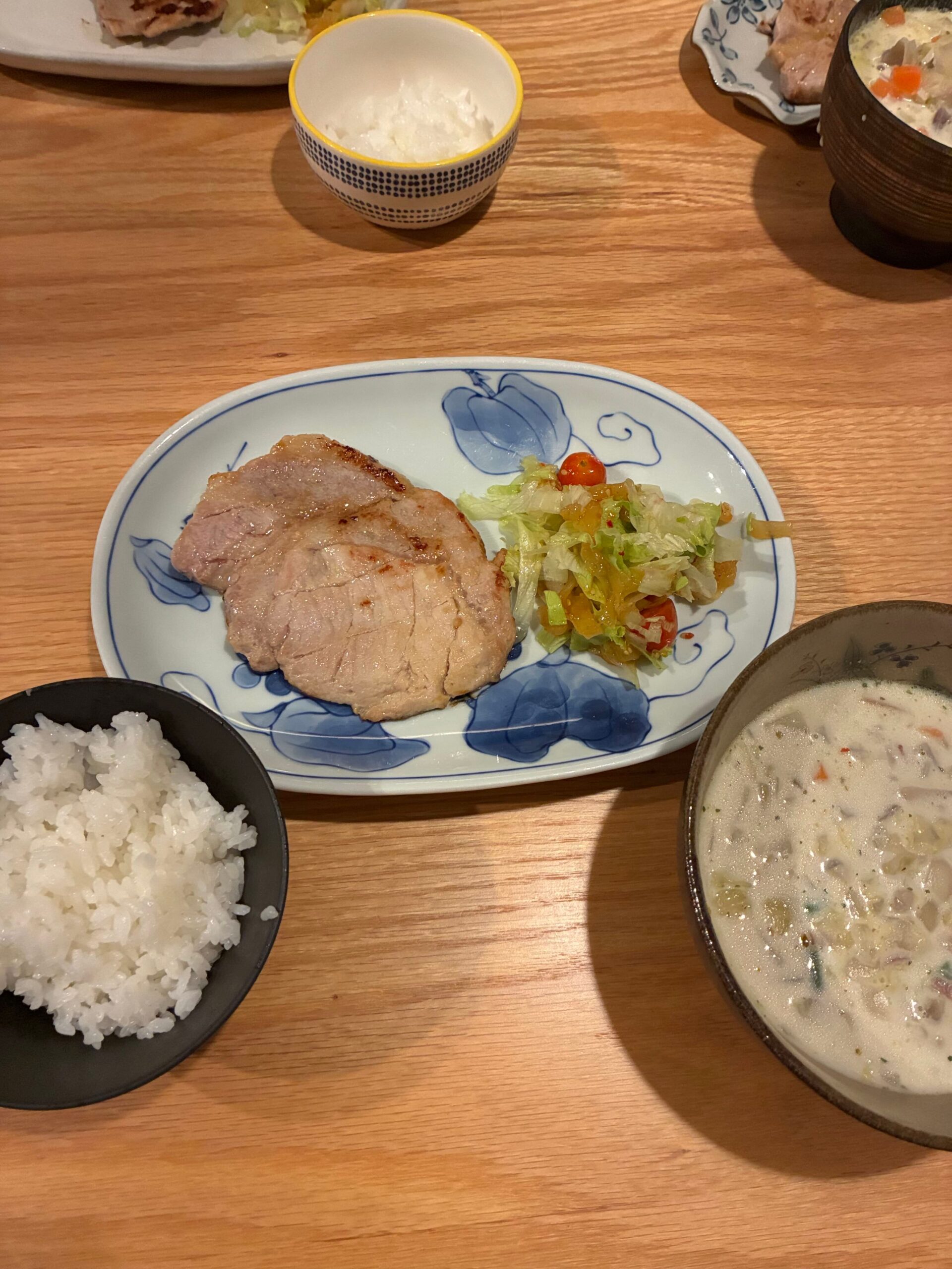 ポークソテーとクラムチャウダーが並んだ家庭の食卓